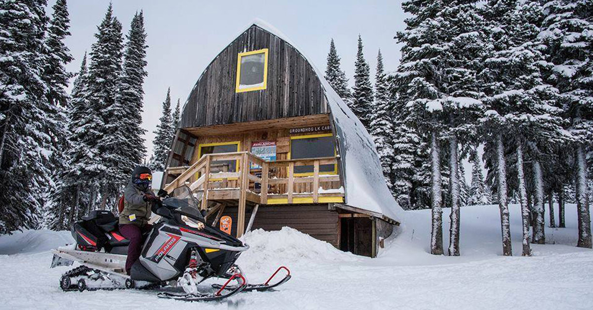 Snowmobiler outside cabin at Groundhog Lake